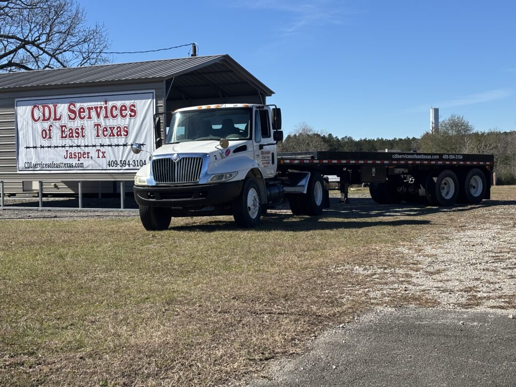 A truck and trailer parked in front of CDL Services of East Texas Building.